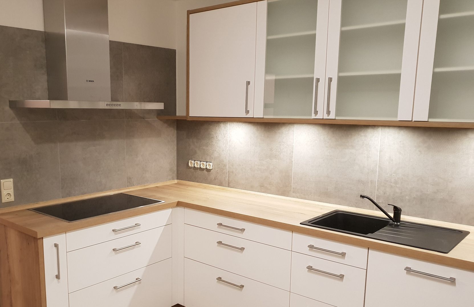 Weiße Küche in L-Form mit Arbeitsplatte in Holzoptik. 