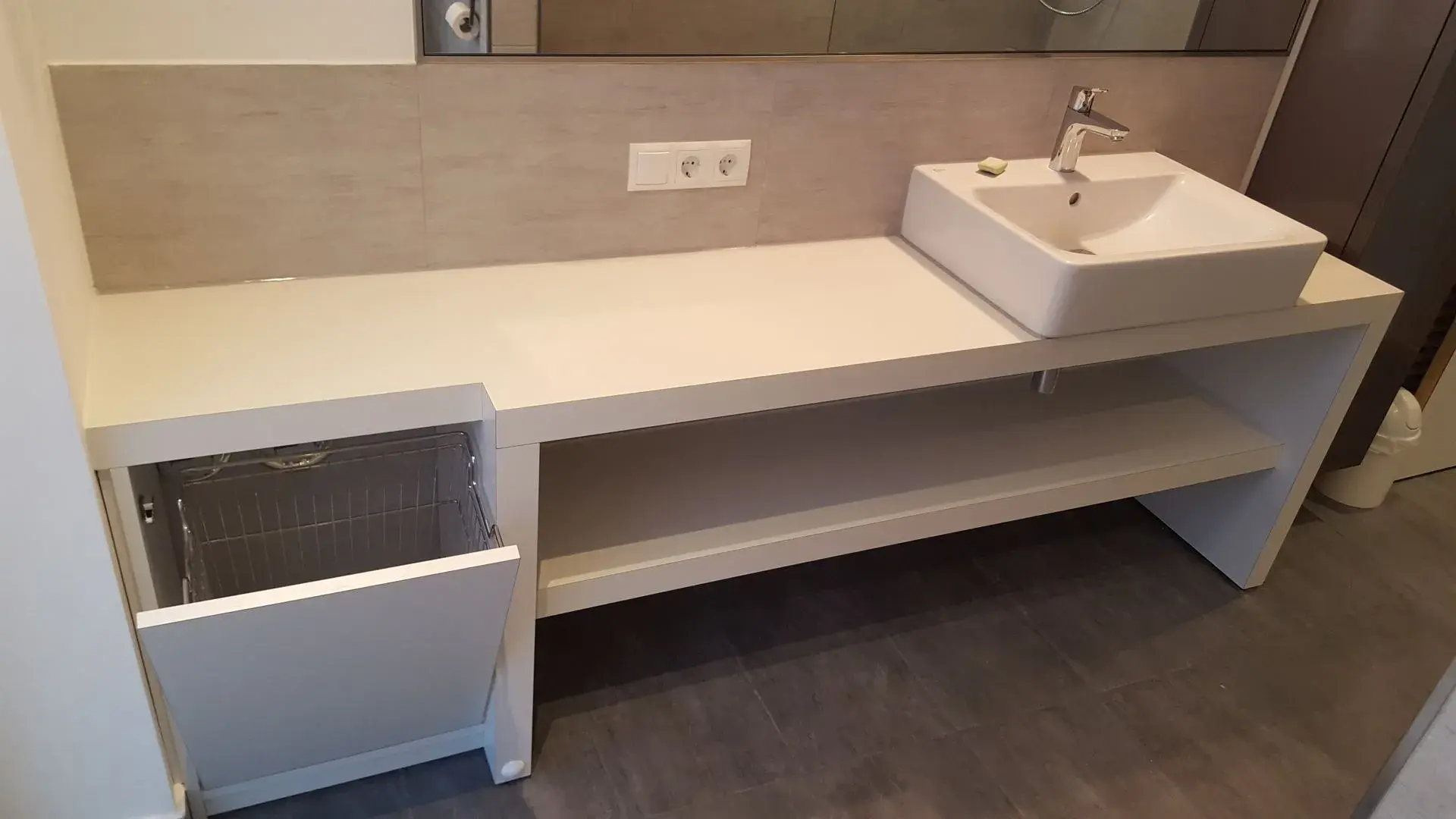 Waschtisch mit Waschbecken und einem eingebauten Wäschekorb. 